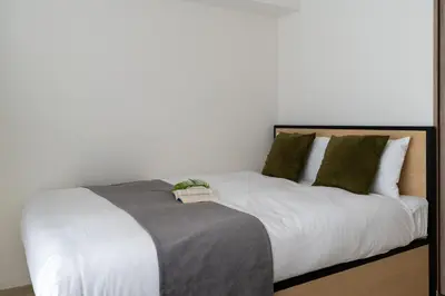 a bed with white sheets and green pillows at \u30b0\u30ed\u30fc\u30d9\u30eb \u30b6 \u30af\u30ec\u30b9\u84b2\u7530 in Tokyo