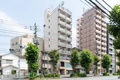 an apartment building with trees in front of a street at \u30b0\u30ed\u30fc\u30d9\u30eb \u30b6 \u30af\u30ec\u30b9\u84b2\u7530 in Tokyo