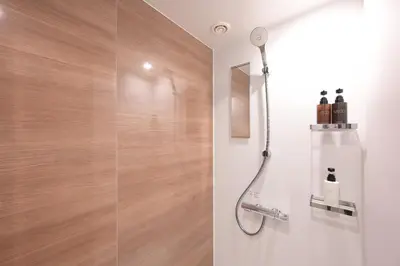 a shower in a bathroom with a wooden wall at COCOYO Hotel \u5927\u585a in Tokyo