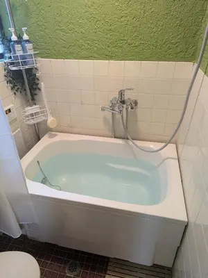 a bath tub with a shower in a bathroom at Matsuri House 20min to Ueno in Tokyo