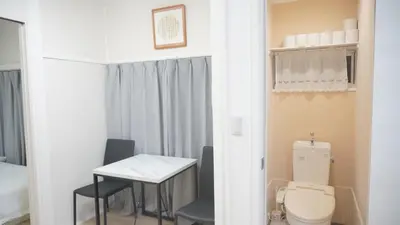 a bathroom with a toilet and a table and chairs at Uhome Tsubame Apartment in Tokyo