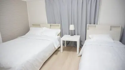 a room with two beds and a table with a lamp at Uhome Tsubame Apartment in Tokyo