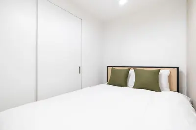 a bedroom with a white bed with green pillows at FK Place\u795e\u697d\u5742 in Tokyo