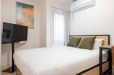 a bedroom with a bed with a flat screen tv at \u30cf\u30fc\u30d0\u30fc\u30ba\u30ec\u30b8\u30c7\u30f3\u30b9\u516b\u5e83 in Tokyo