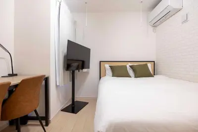 a bedroom with a bed and a desk with a television at \u30cf\u30fc\u30d0\u30fc\u30ba\u30ec\u30b8\u30c7\u30f3\u30b9\u516b\u5e83 in Tokyo