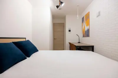 a bedroom with a white bed and a brick wall at \u30cf\u30fc\u30d0\u30fc\u30ba\u30ec\u30b8\u30c7\u30f3\u30b9\u516b\u5e83 in Tokyo