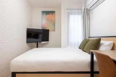 a bedroom with a bed and a flat screen tv at \u30cf\u30fc\u30d0\u30fc\u30ba\u30ec\u30b8\u30c7\u30f3\u30b9\u516b\u5e83 in Tokyo