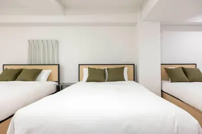 two beds in a room with white sheets and green pillows at APRO Stay \u54c1\u5ddd in Tokyo