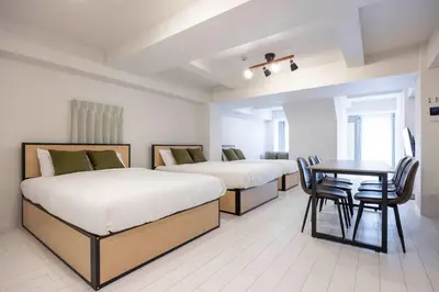 two beds in a room with a table and chairs at APRO Stay \u54c1\u5ddd in Tokyo