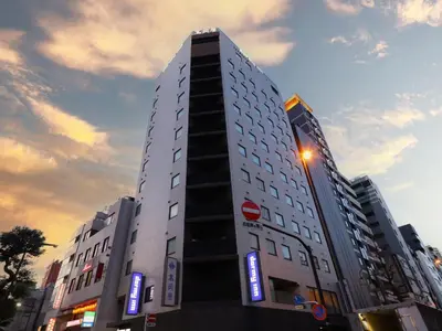 a tall white building with blue signs on it at Dormy Inn Ueno Okachimachi in Tokyo