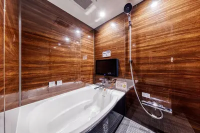 a bathroom with a tub and a tv on the wall at SweetsHotel Ikebukuro -Adult Only in Tokyo