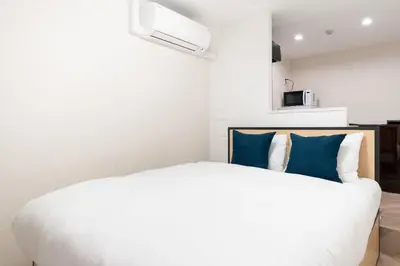 a bedroom with a white bed with blue pillows at Contel\u660e\u5927\u524d in Tokyo