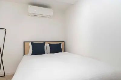 a white bed with blue pillows in a bedroom at Contel\u660e\u5927\u524d in Tokyo