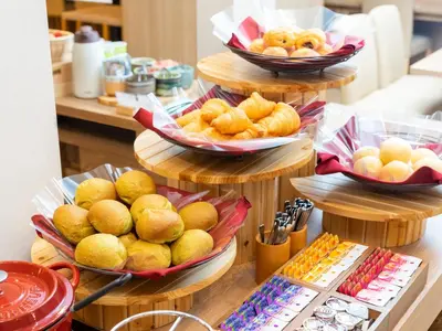 a display of bread and pastries on plates on a counter at Super Hotel Ikebukuro-Eki Kitaguchi in Tokyo