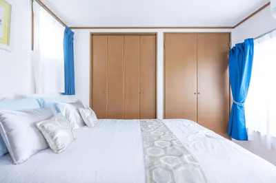 a bedroom with a large white bed with blue curtains at NEW Koenji House 3BR Family Friendly Haven in Tokyo