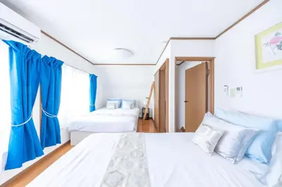 two beds in a room with blue curtains at NEW Koenji House 3BR Family Friendly Haven in Tokyo
