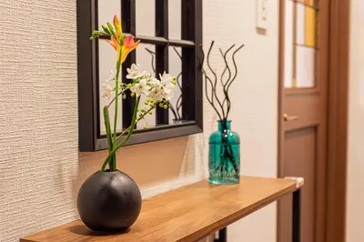 a vase with flowers on a table with a mirror at IROHA STAY HANEDA - Family-Friendly Home Stay near Haneda with Great Access to Tokyo & Yokohama in Tokyo