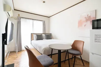 a bedroom with a bed and a table and chairs at \u30a8\u30b9\u30ab\u30eb\u690e\u540d\u753a in Tokyo