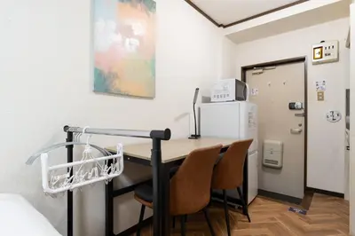 a room with a desk with chairs and a refrigerator at \u30a8\u30b9\u30ab\u30eb\u690e\u540d\u753a in Tokyo