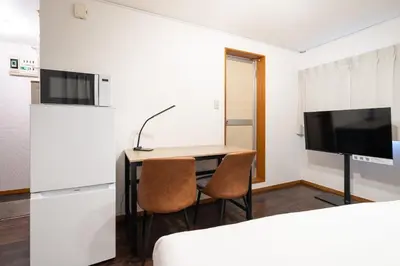 a room with a desk with two chairs and a television at \u30e1\u30be\u30f3\u7d4c\u5802 in Tokyo