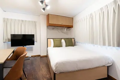 a bedroom with a bed and a desk and a tv at \u30e1\u30be\u30f3\u7d4c\u5802 in Tokyo