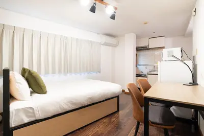 a bedroom with a bed and a table and a kitchen at \u30e1\u30be\u30f3\u7d4c\u5802 in Tokyo