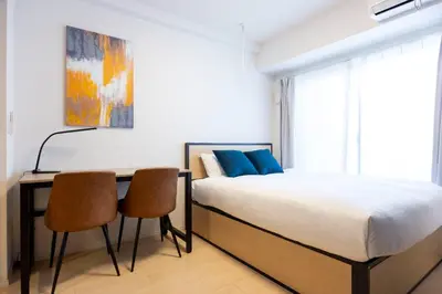 a bedroom with a bed and a desk with two chairs at \u30f4\u30a3\u30e9\u4e21\u56fd in Tokyo