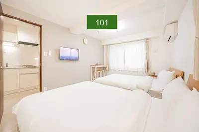 two beds in a hotel room with a sign that reads at Shinjuku Downtown 1min walk to metro Cozy APT in Tokyo
