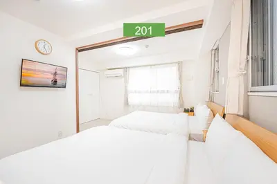 a bedroom with two beds and a clock on the wall at Shinjuku Downtown 1min walk to metro Cozy APT in Tokyo