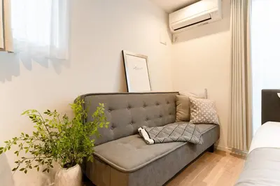 a couch in a living room with a plant at Sangenjaya Modern Stay in Tokyo
