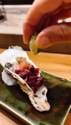 a person holding a piece of food on a green plate at Sangenjaya Modern Stay in Tokyo