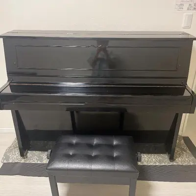 a black piano with a black leather seat at \u6771\u4eac\u5c0f\u5ca9\u4e0e\u623f\u4e1c\u540c\u4f4fmishe in Tokyo