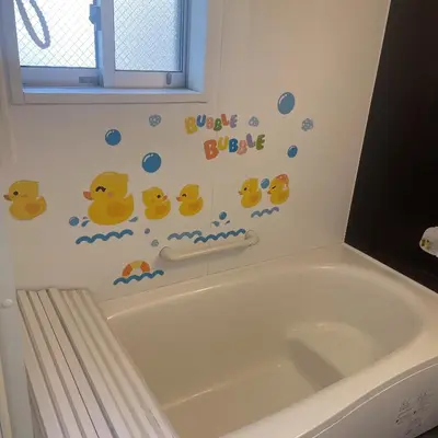 a bathroom with a bath tub with stickers on the wall at \u6771\u4eac\u5c0f\u5ca9\u4e0e\u623f\u4e1c\u540c\u4f4fmishe in Tokyo