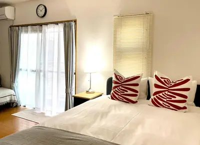 a bedroom with a large bed with red and white pillows at \u65b0\u5bbf\u4e00\u7ad95\u5206\u949f-303-\u9910\u9986\u8d2d\u7269\u8857-\u5b89\u9759\u54c1\u8d28\u516c\u5bd3-\u76f4\u8fbe\u7687\u5c45\u79cb\u53f6\u539f in Tokyo