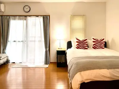 a bedroom with a bed and a window with a clock at \u65b0\u5bbf\u4e00\u7ad95\u5206\u949f-303-\u9910\u9986\u8d2d\u7269\u8857-\u5b89\u9759\u54c1\u8d28\u516c\u5bd3-\u76f4\u8fbe\u7687\u5c45\u79cb\u53f6\u539f in Tokyo