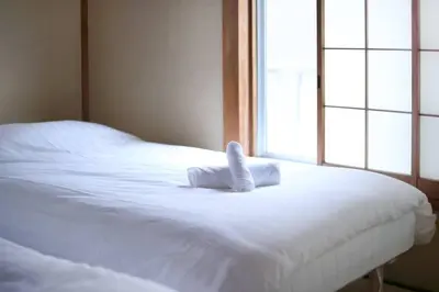 a white bed with a towel on top of it at Machiya \u4eac Asakusa in Tokyo