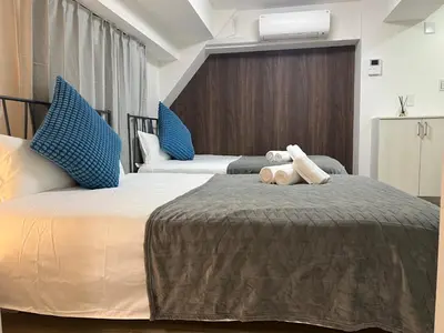 two beds in a hotel room with blue pillows at Ikebukuro Area R2 NishiikeApartment 5F No Elevator in Tokyo