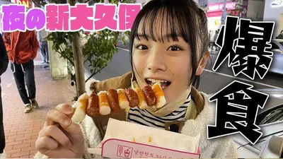 a woman eating a hot dog with bacon at New Open\u6771\u65b0\u5bbf \u6238\u5efa in Tokyo