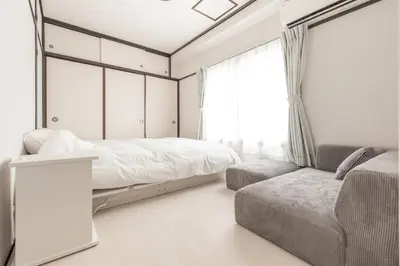 a bedroom with a bed and a couch and a window at Waseda BNB Shinjuku in Tokyo