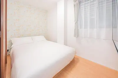 a white bedroom with a bed and a window at Waseda BNB Shinjuku in Tokyo