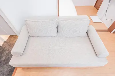 a white couch with two pillows on a wooden floor at Waseda BNB Shinjuku in Tokyo