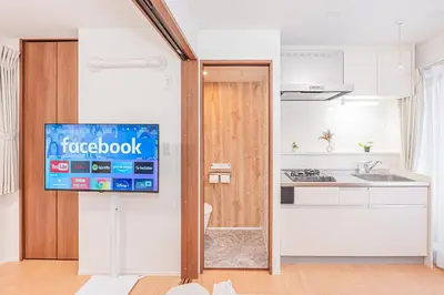 a kitchen with a tv on the wall next to a kitchen at Waseda BNB Shinjuku in Tokyo