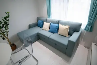 a blue couch with pillows on it in a living room at \u30bb\u30ec\u30b9\u516b\u5e83101\u5ba4 24\u5e7410\u6708\u65b0\u305f\u306b\u30aa\u30fc\u30d7\u30f3 \u516b\u5e83\u99c5\u5f92\u6b699\u5206 \u53ce\u5bb9\u4eba\u65708 \u8cb8\u5207 \u5bdd\u5ba42 in Tokyo