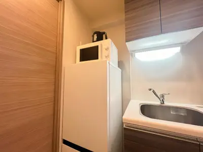 a kitchen with a sink and a microwave on top of a refrigerator at Shinjuku Downtown BZT Free WiFi in Tokyo