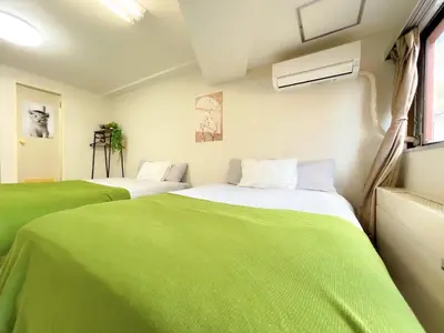two beds in a room with green sheets at Shinjuku West Cozy WZE Free WiFi in Tokyo