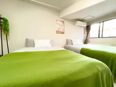 two beds in a room with green sheets at Shinjuku West Cozy WZE Free WiFi in Tokyo