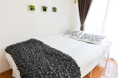 a white bed with a black blanket and flowers on it at \u30cf\u30a4\u30af\u30ec\u30b9\u30c8\u4e2d\u91ce203 in Tokyo