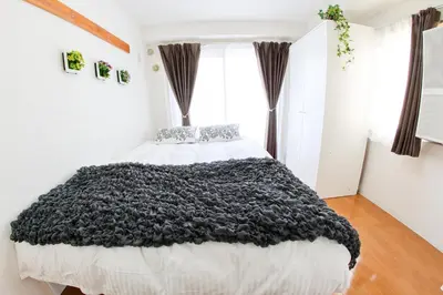 a bedroom with a large bed with a black blanket at \u30cf\u30a4\u30af\u30ec\u30b9\u30c8\u4e2d\u91ce203 in Tokyo