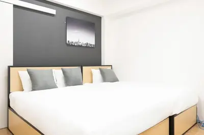 a bedroom with a white bed with a tv on the wall at \u30c0\u30fc\u30a6\u30a3\u30f3\u795e\u697d\u5742 in Tokyo