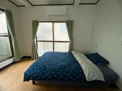 a bedroom with a bed with a blue comforter and a window at \u5343\u77f3\u5bb6 in Tokyo